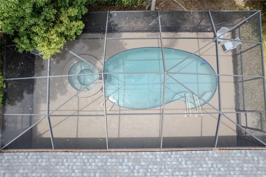An aerial view of a screened-in swimming pool and spa on a concrete patio — 7999 SW 187TH AVENUE, DUNNELLON, FL