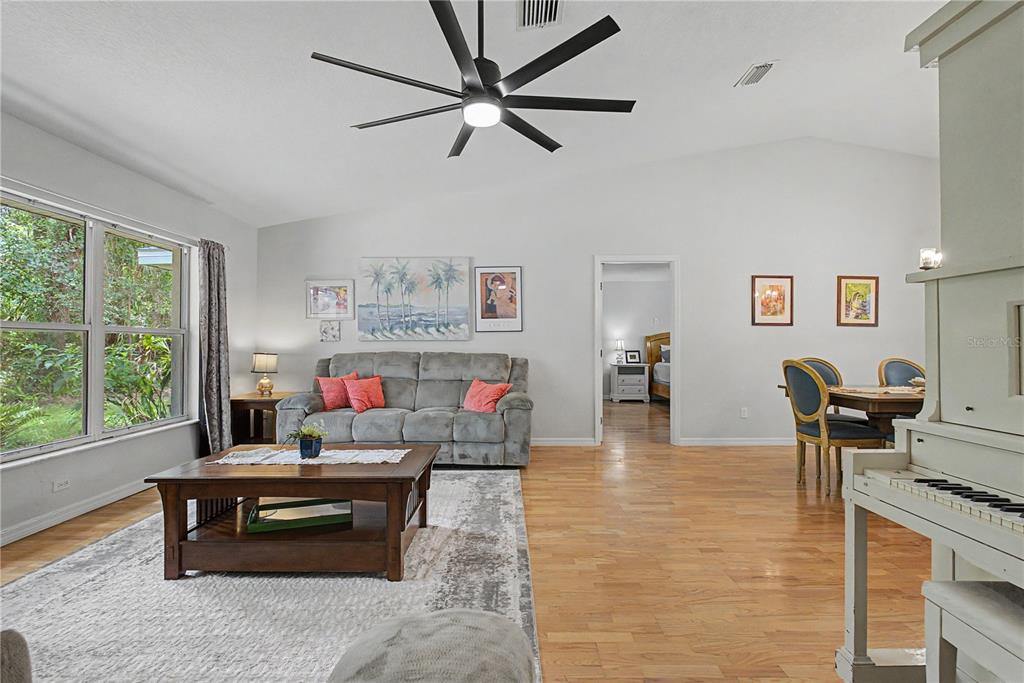 A living room features a grey sofa, a wooden coffee table, and a white piano — 7999 SW 187TH AVENUE, DUNNELLON, FL