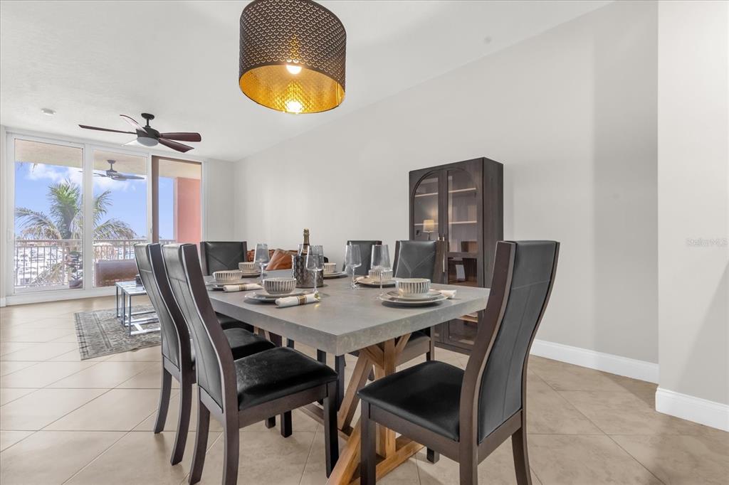 A dining room features a gray table, dark chairs, a pendant light, and a balcony — 606 RIVIERA DUNES WAY UNIT 207, PALMETTO, FL