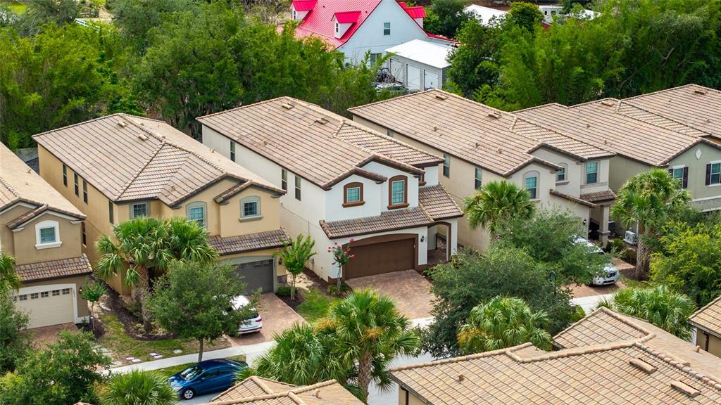 An aerial view shows several suburban houses with tiled roofs and driveways surrounded by trees — 1885 NICE COURT, KISSIMMEE, FL