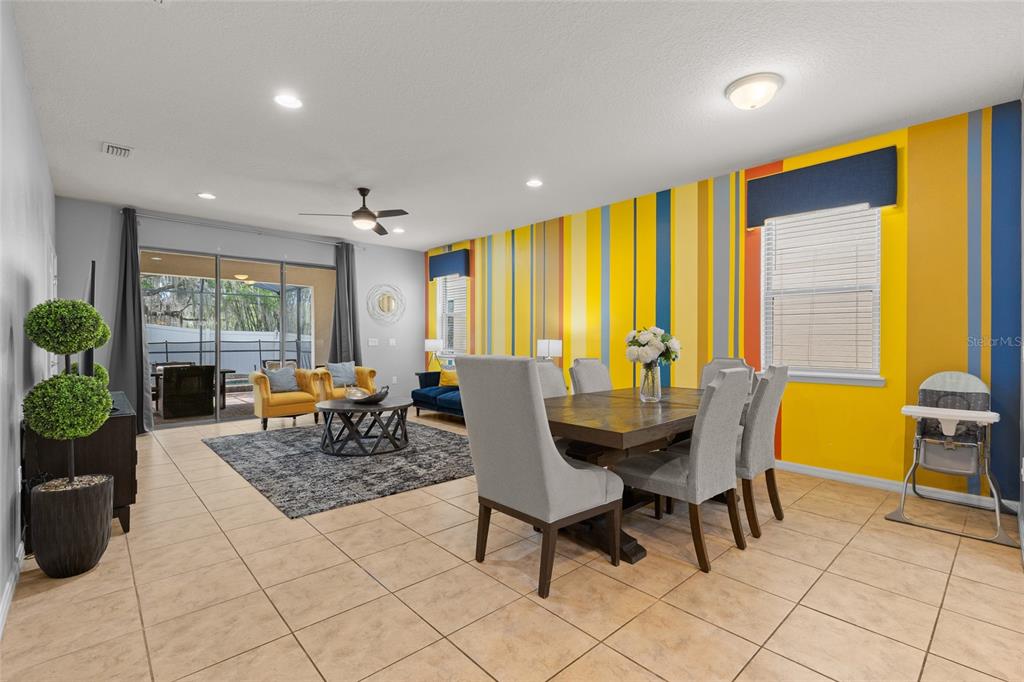 A dining and living area features a striped accent wall, tile floors, and gray furniture — 1885 NICE COURT, KISSIMMEE, FL