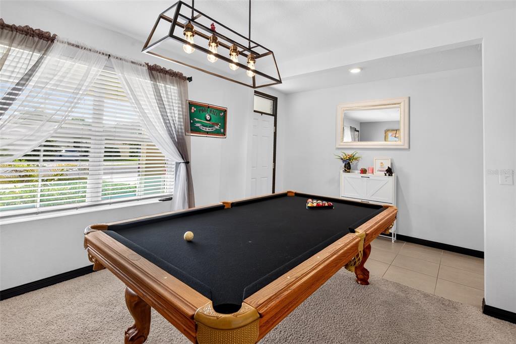 A game room features a pool table with a black felt surface under a pendant light — 7043 SILVERADO RANCH BOULEVARD, ZEPHYRHILLS, FL