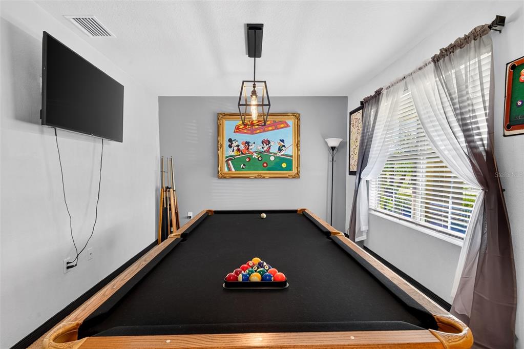 A game room features a pool table, a wall-mounted television, and a Mickey Mouse painting — 7043 SILVERADO RANCH BOULEVARD, ZEPHYRHILLS, FL