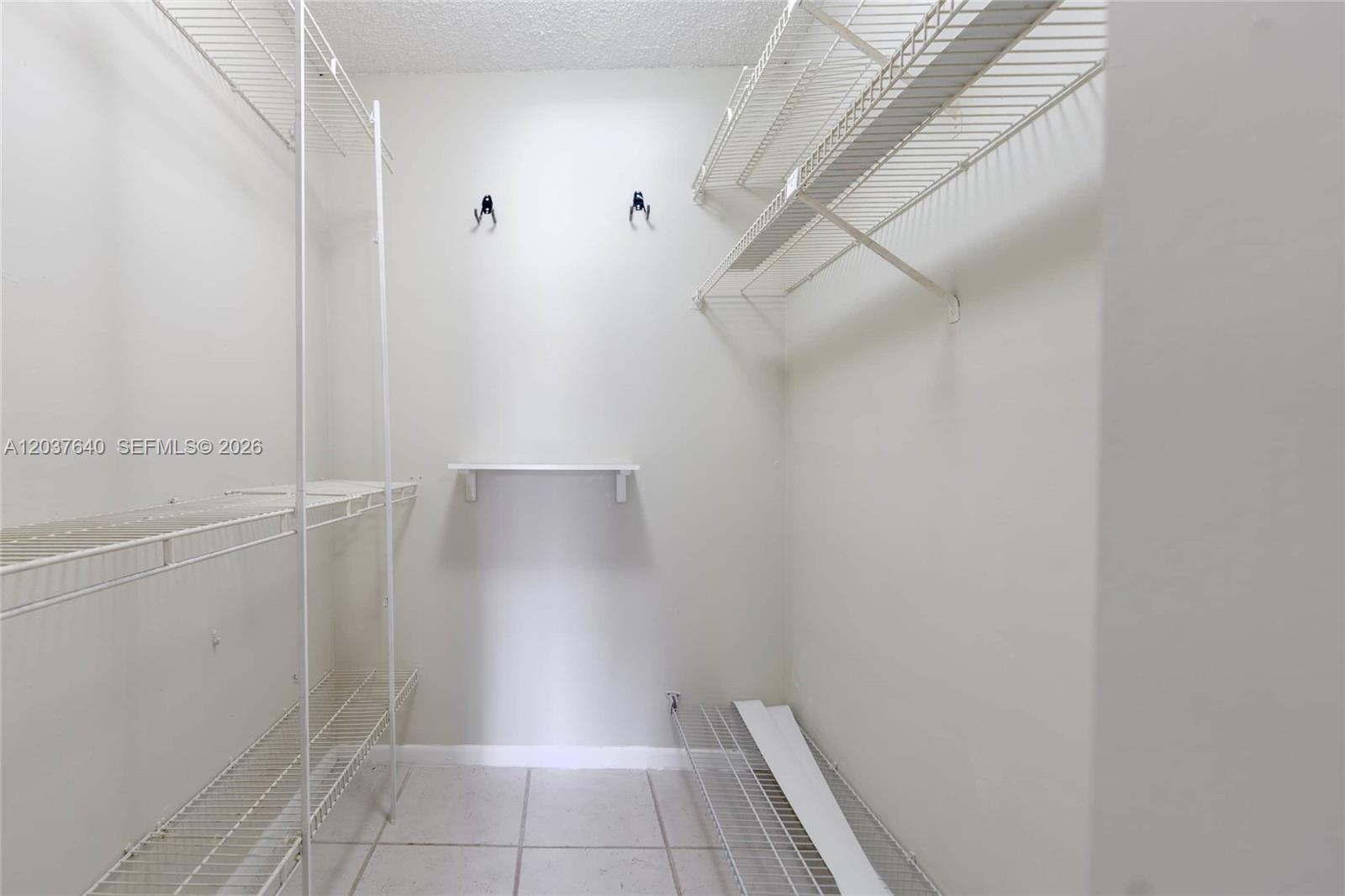 A walk-in closet features white wire shelving, a small wall-mounted shelf, and tiled flooring — 9015 SW 125th Ave # N207, Miami FL 33186, MIAMI, FL