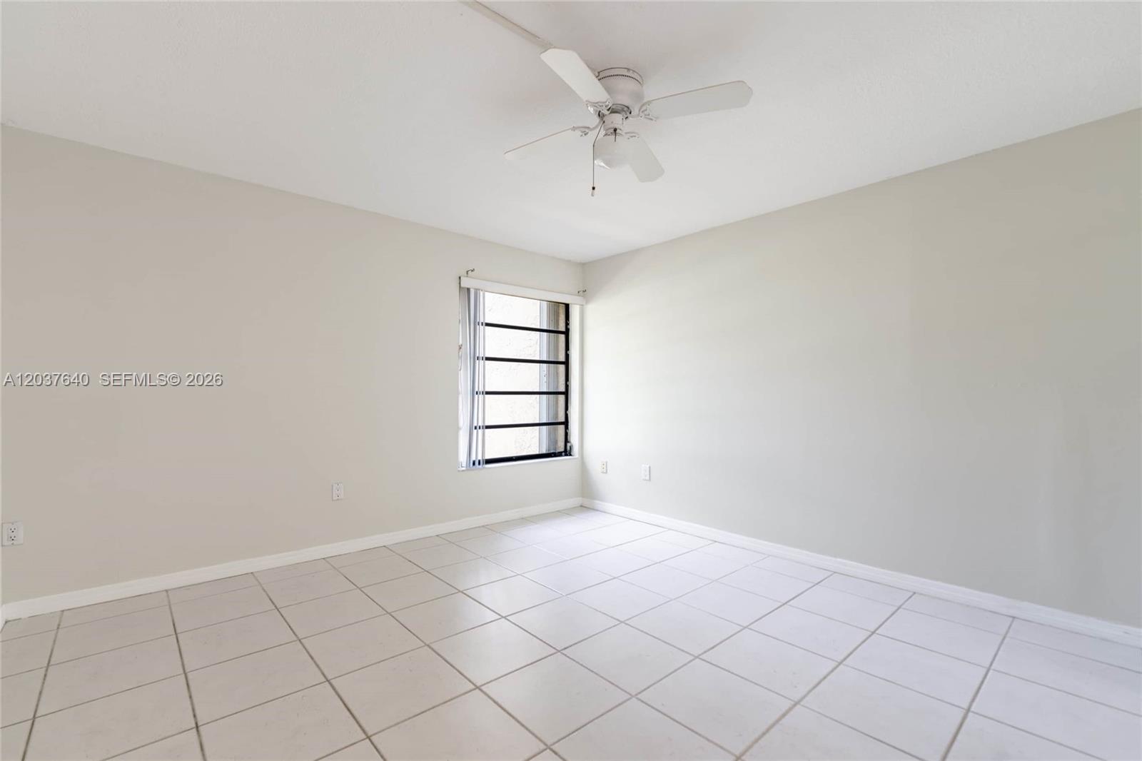 An empty bedroom with white tile floors, beige walls, and a ceiling fan — 9015 SW 125th Ave # N207, Miami FL 33186, MIAMI, FL