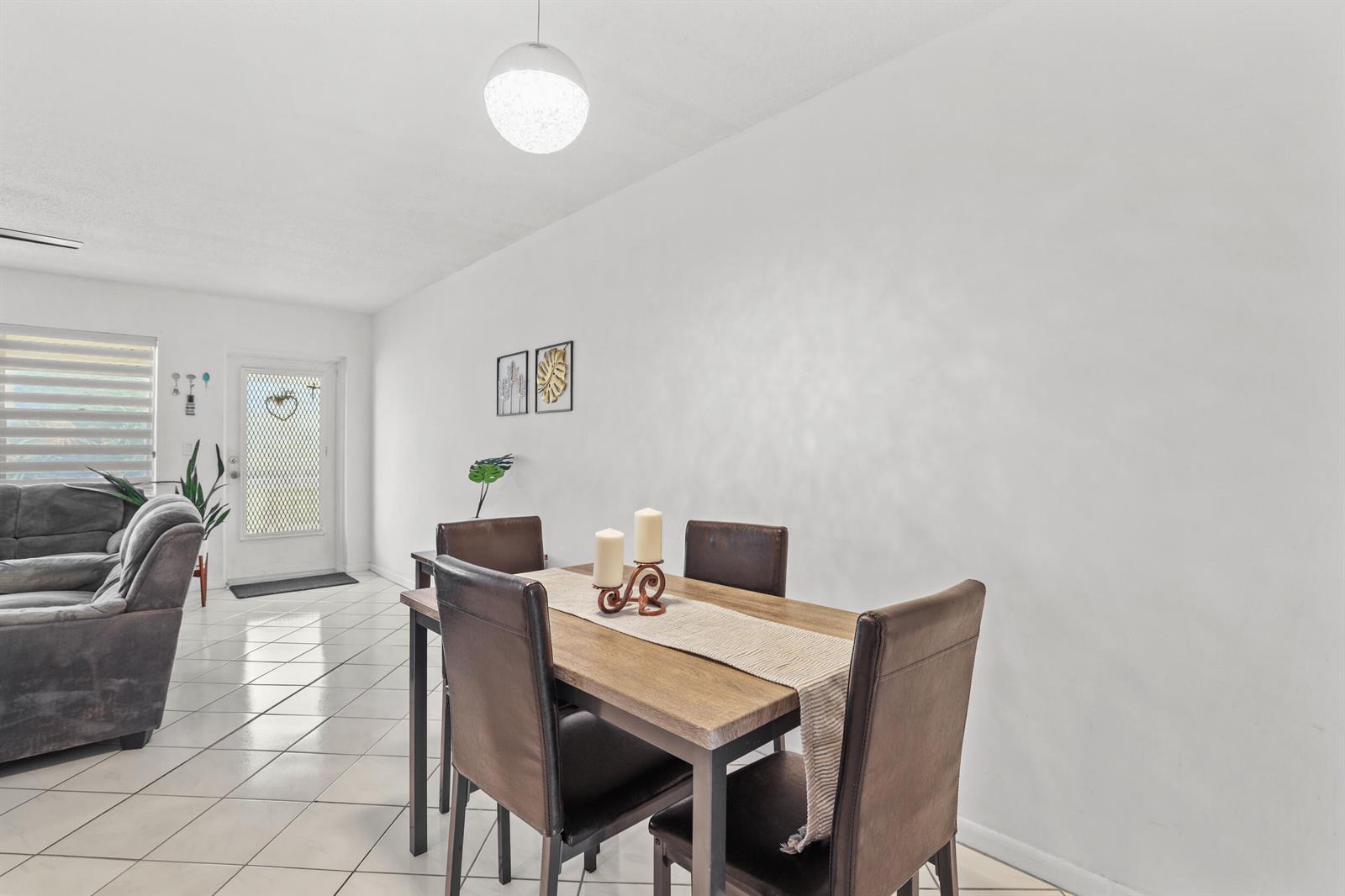 A dining area with a wooden table and chairs sits on a tiled floor — 215 Sheffield I, West Palm Beach FL 33417, WEST PALM BEACH, FL