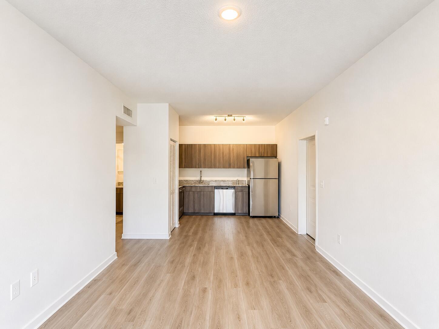 A kitchen with wood-toned cabinets and stainless steel appliances sits at the end of a room — 4250 Lakewood Road # 204, FL 33461, FL