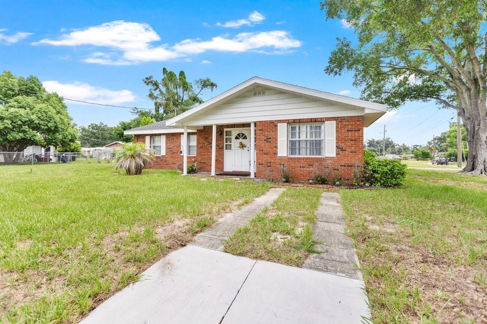 A single-story brick house with a white front door and a concrete driveway — 132 ANARECE AVENUE, AUBURNDALE, FL