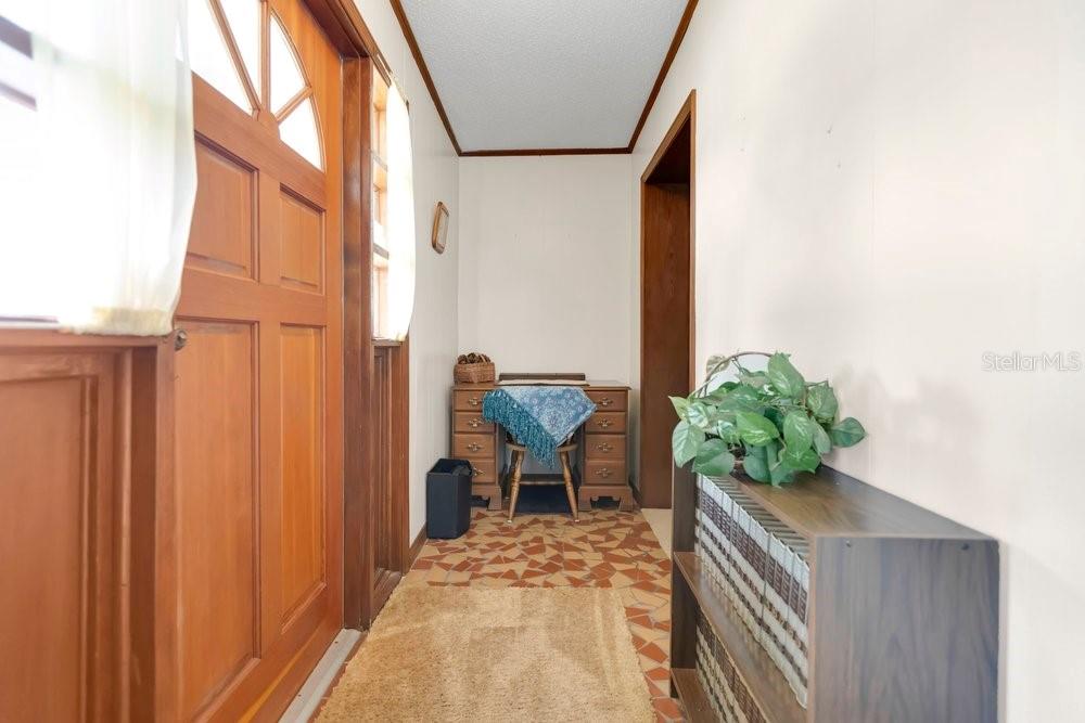 A narrow entryway features a wooden front door, tiled flooring, and a small wooden desk — 132 ANARECE AVENUE, AUBURNDALE, FL
