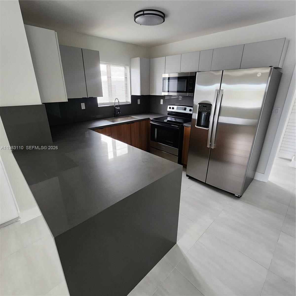 A kitchen features gray cabinets, stainless steel appliances, and a dark gray countertop peninsula — 1171 NW 66th St # 1173, Miami FL 33150, MIAMI, FL