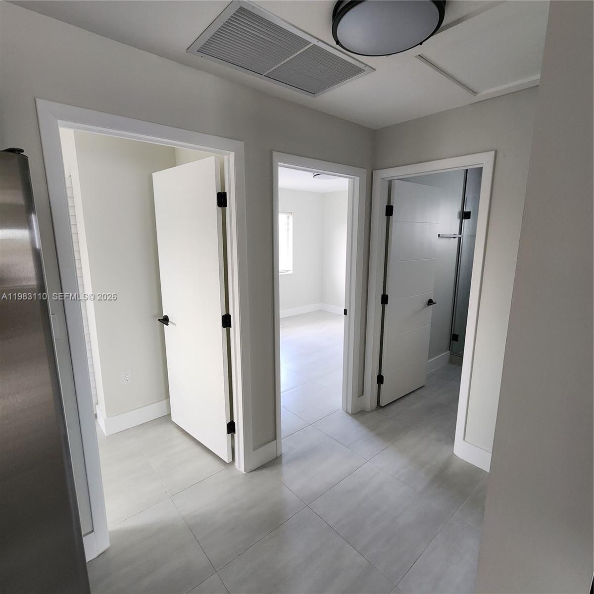 A hallway with light gray tile flooring leads to three doorways in a residential interior — 1171 NW 66th St # 1173, Miami FL 33150, MIAMI, FL