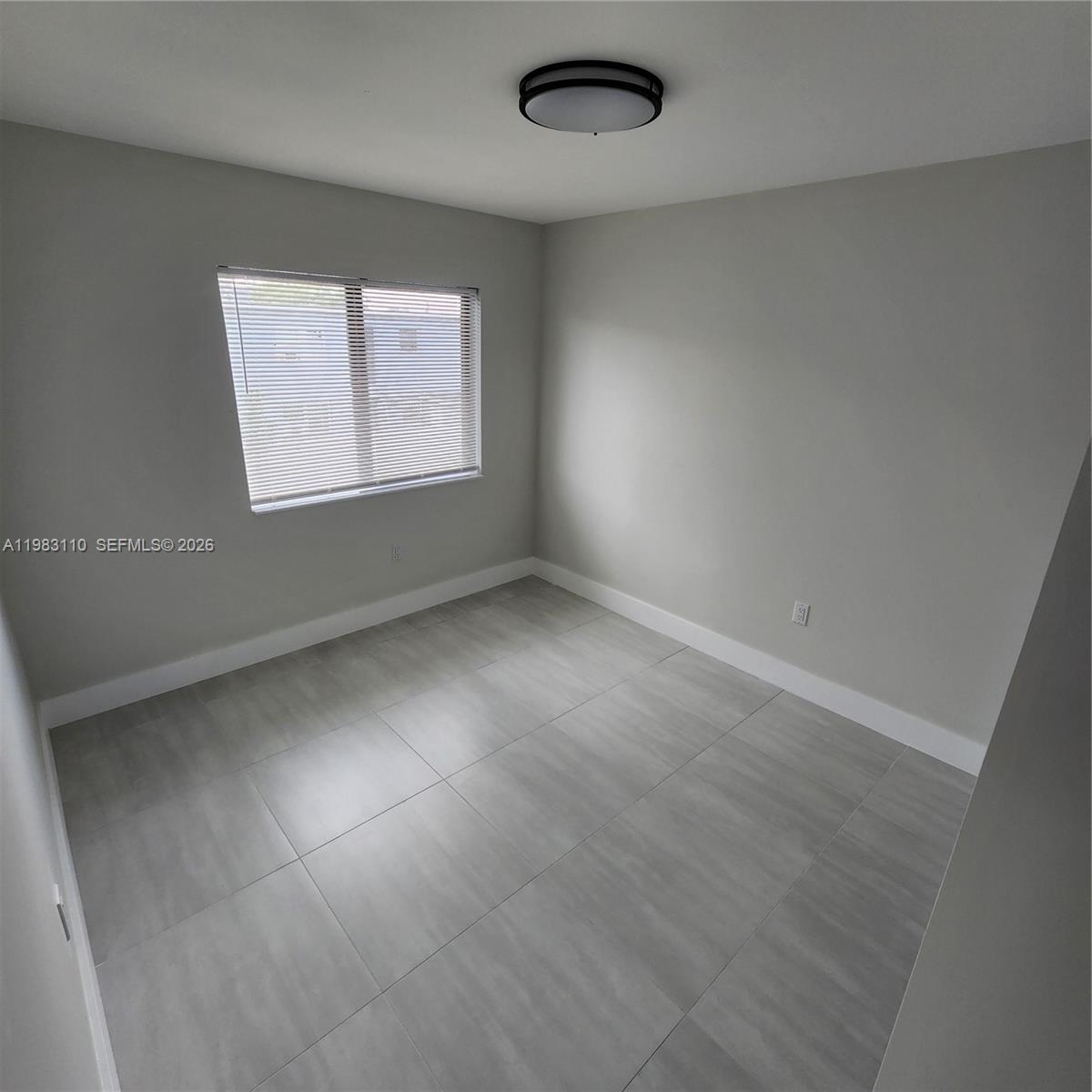 An empty room features light gray walls, large gray floor tiles, and a ceiling light — 1171 NW 66th St # 1173, Miami FL 33150, MIAMI, FL