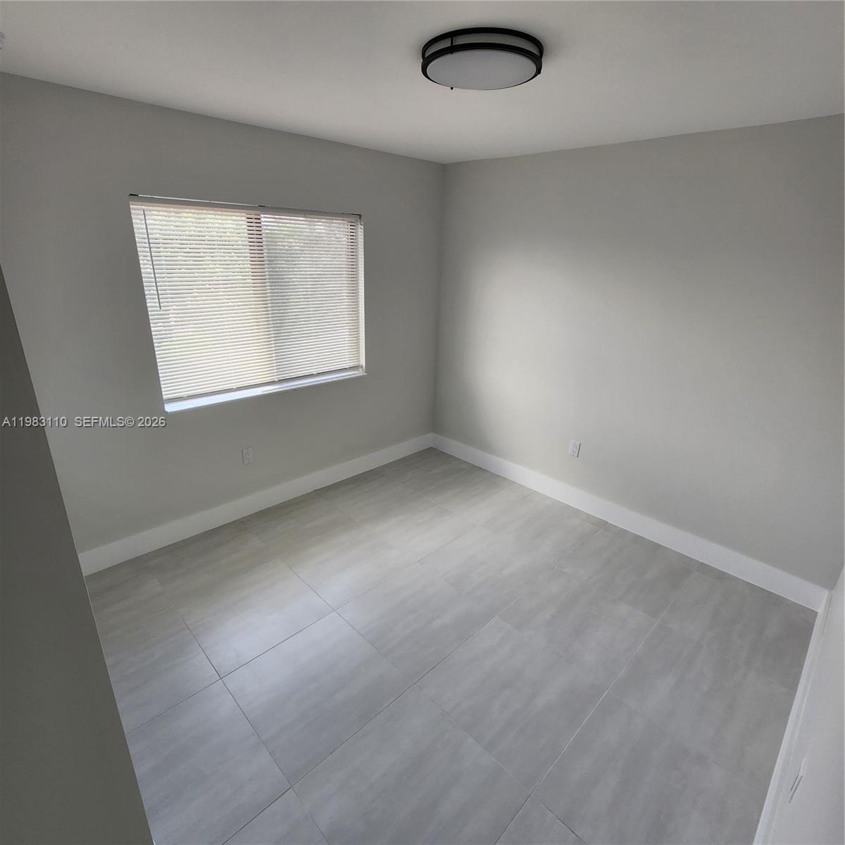 An empty bedroom features light gray walls, large square floor tiles, and a ceiling light — 1171 NW 66th St # 1173, Miami FL 33150, MIAMI, FL