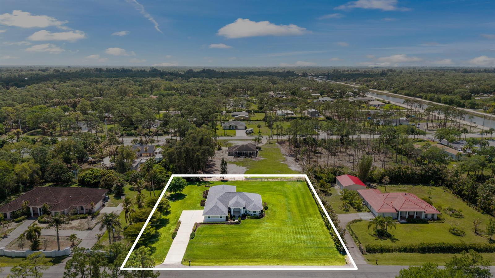An aerial view shows a single-story house with a large lawn and a driveway — 12878 N 70th Pl Place N, FL 33412, FL