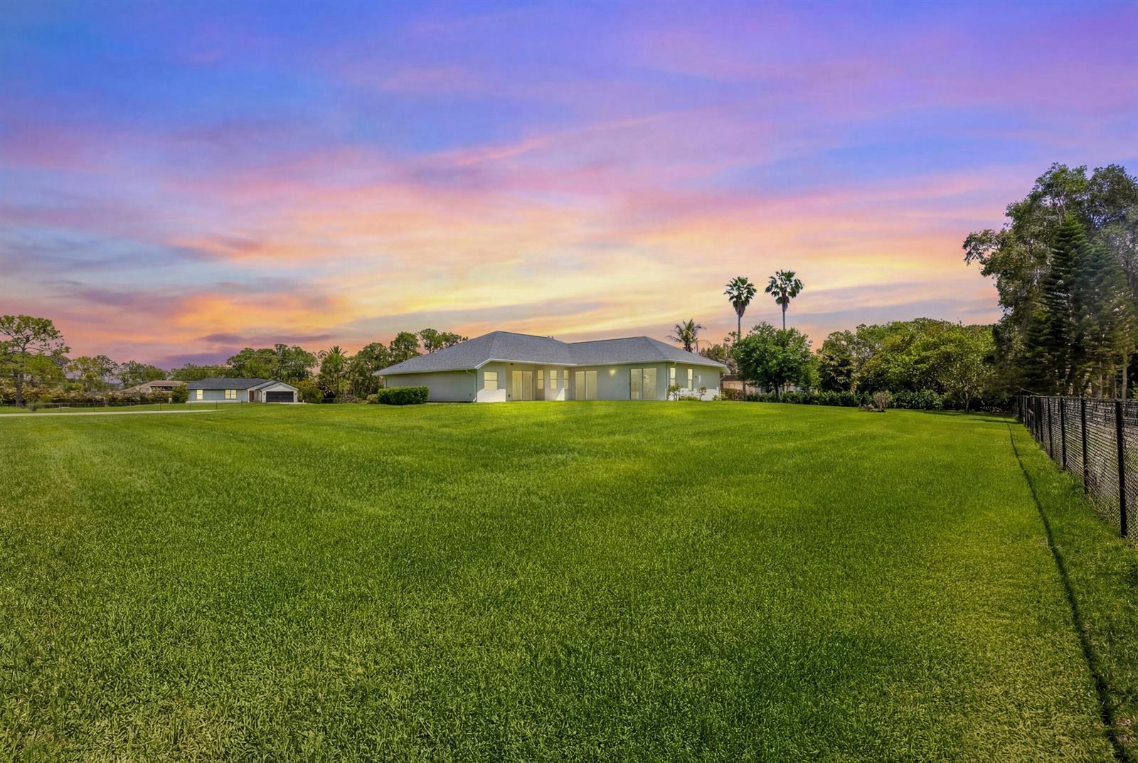 A single-story house with a large green lawn under a colorful sunset sky — 12878 N 70th Pl Place N, FL 33412, FL