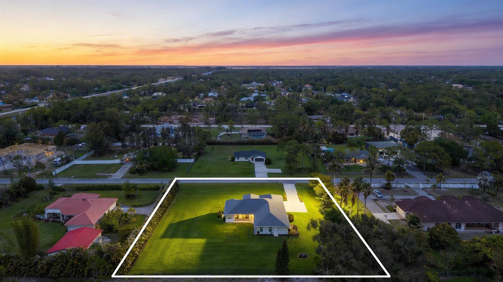 An aerial view shows a single-story house with a large lawn at sunset — 12878 N 70th Pl Place N, FL 33412, FL