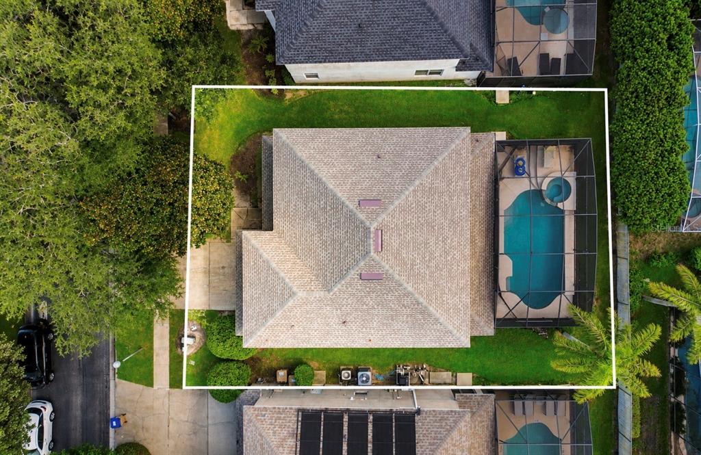 An aerial view shows a house with a shingled roof, a screened pool, and surrounding landscaping — 8027 ACADIA ESTATES COURT, KISSIMMEE, FL