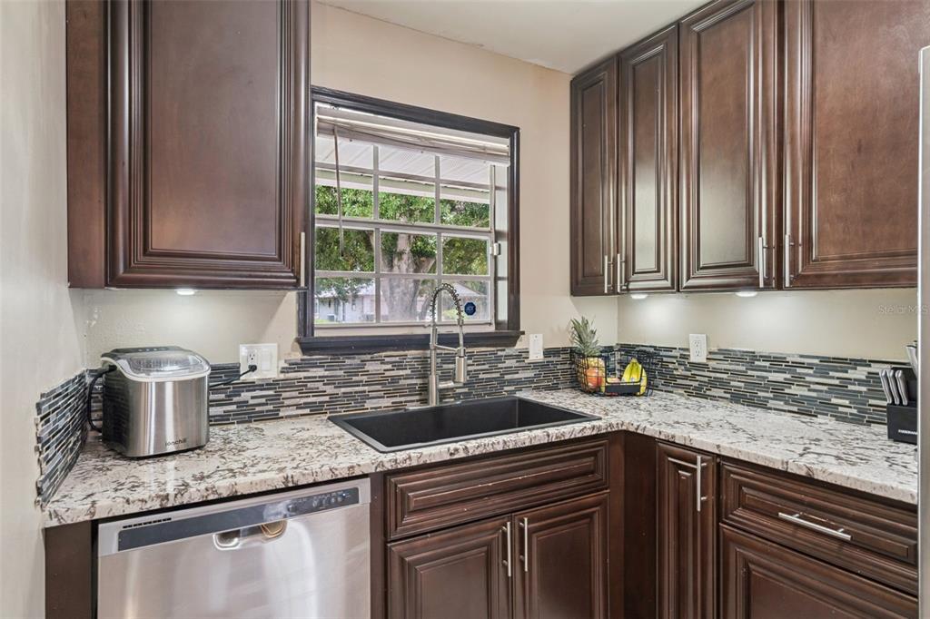 A kitchen features dark wood cabinets, granite countertops, a black sink, and a tiled backsplash — 3102 GARDEN COURT, ST CLOUD, FL
