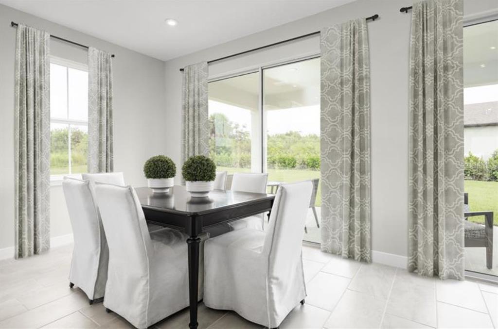 A dining area features a dark table, white slipcovered chairs, patterned curtains, and sliding glass doors — 2879 NILGIRI STREET NW, PALM BAY, FL