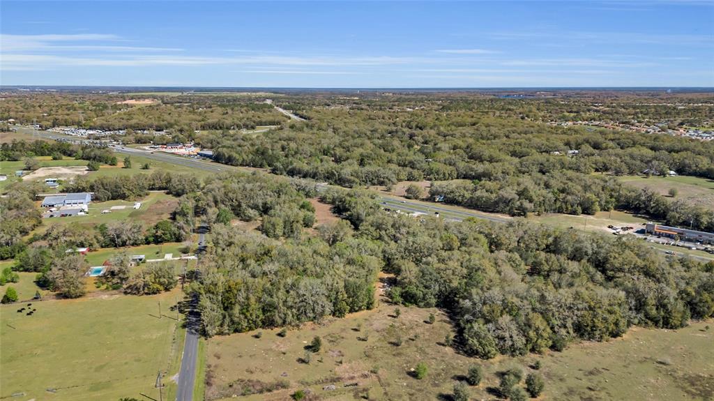 An aerial view shows a large, wooded lot adjacent to a highway and open fields — 00 HWY 441 AND SE 135TH ST., SUMMERFIELD, FL