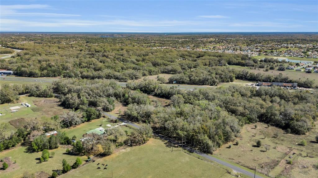 An aerial view shows a rural property with a house, trees, and a nearby highway — 00 HWY 441 AND SE 135TH ST., SUMMERFIELD, FL