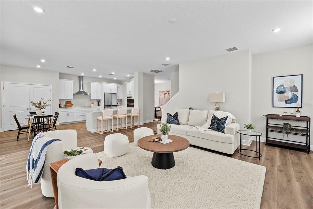 An open-concept living room and kitchen featuring light wood flooring, white cabinetry, and neutral furniture — 6244 29TH STREET N, ST PETERSBURG, FL