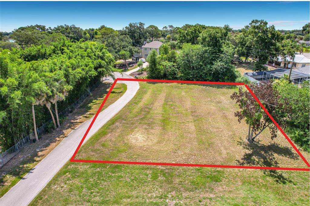 An aerial view shows a vacant, rectangular grassy lot outlined in red next to a road — BROGDEN COURT SE, WINTER HAVEN, FL