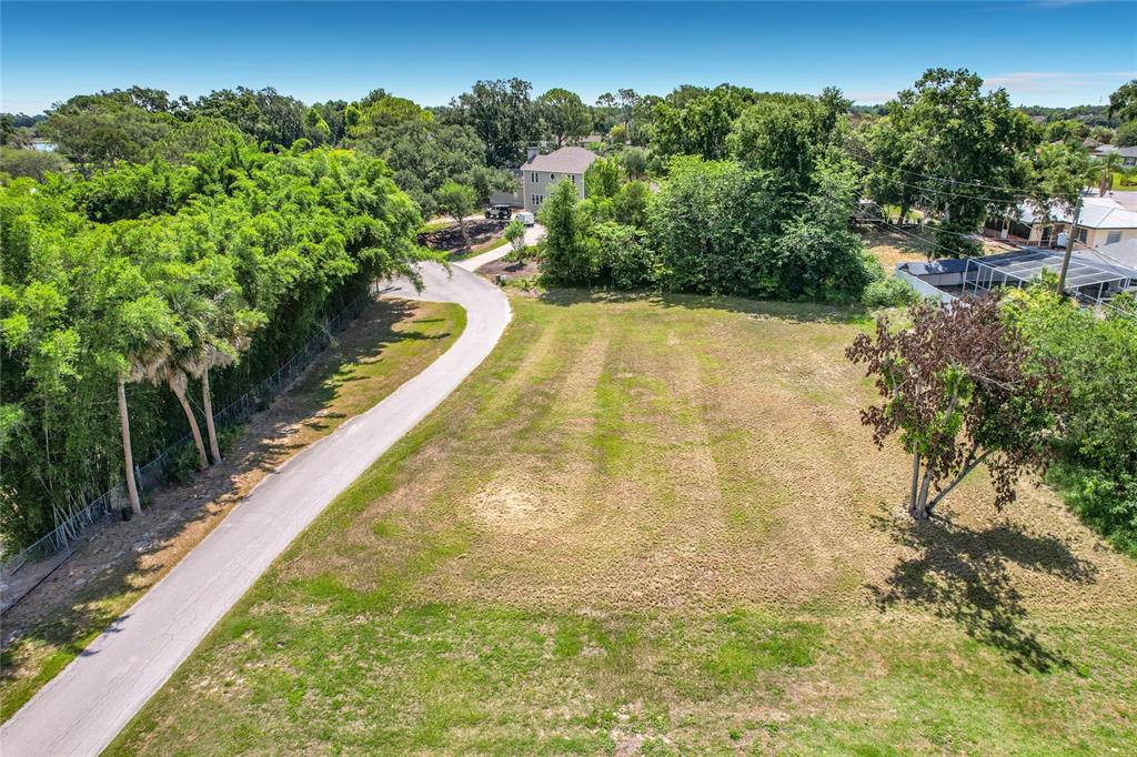 An aerial view shows a vacant, grassy residential lot adjacent to a paved driveway — BROGDEN COURT SE, WINTER HAVEN, FL