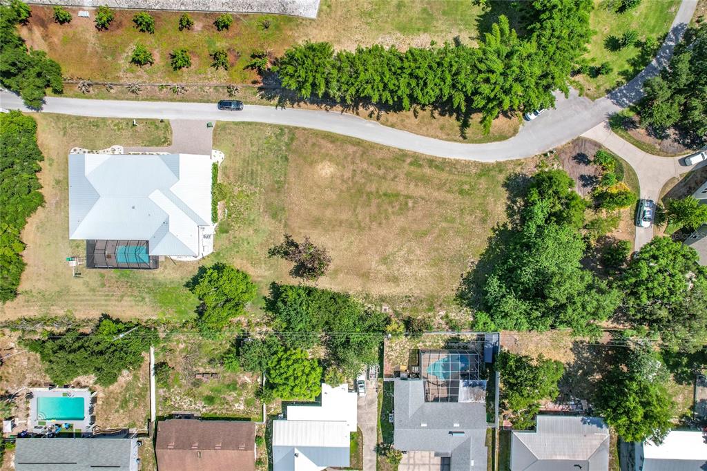 An aerial view shows a vacant residential lot situated between two houses with swimming pools — BROGDEN COURT SE, WINTER HAVEN, FL