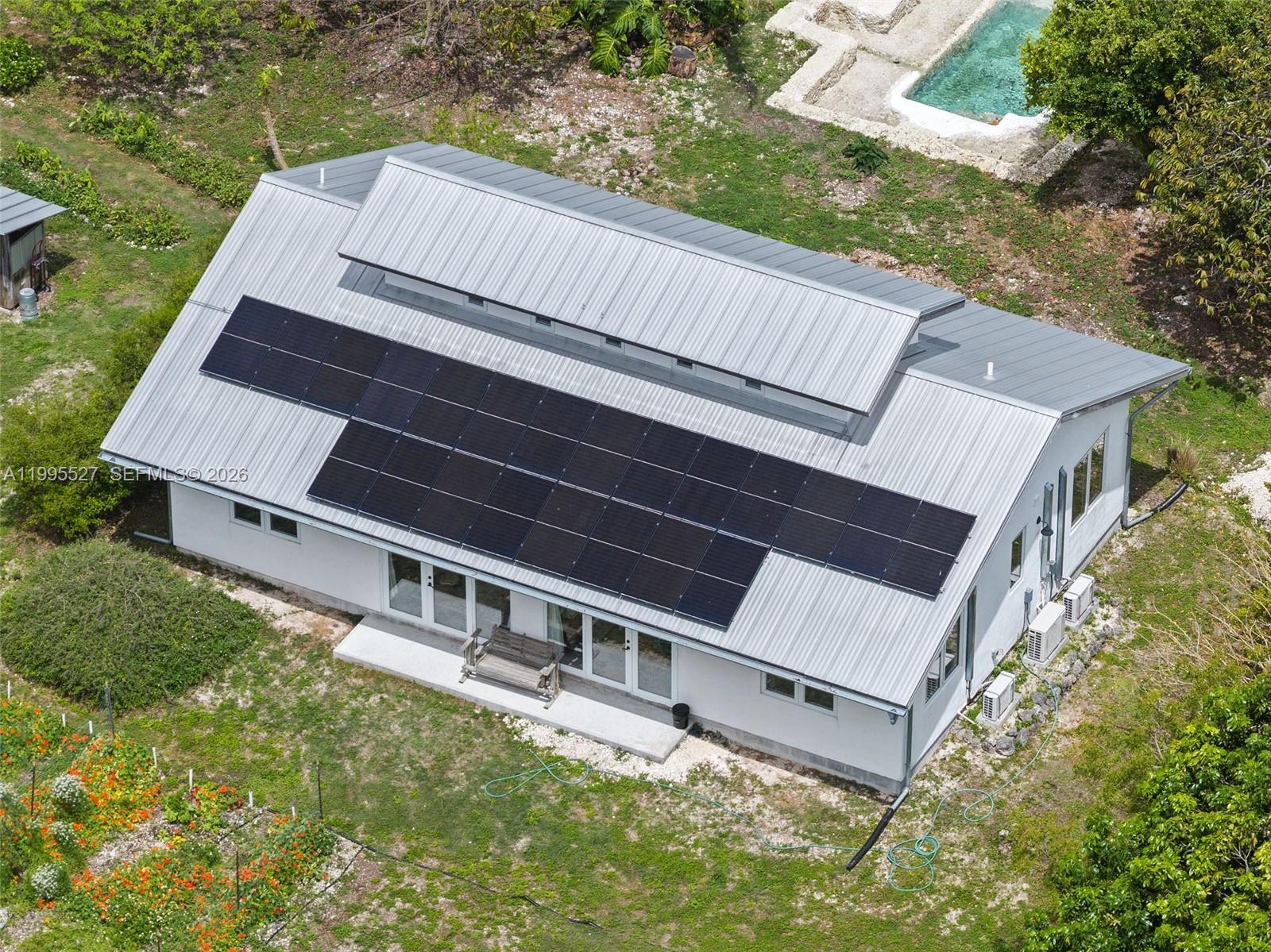 An aerial view shows a white house with a metal roof and solar panels — 20255 SW 154th Ave, Miami FL 33187, MIAMI, FL