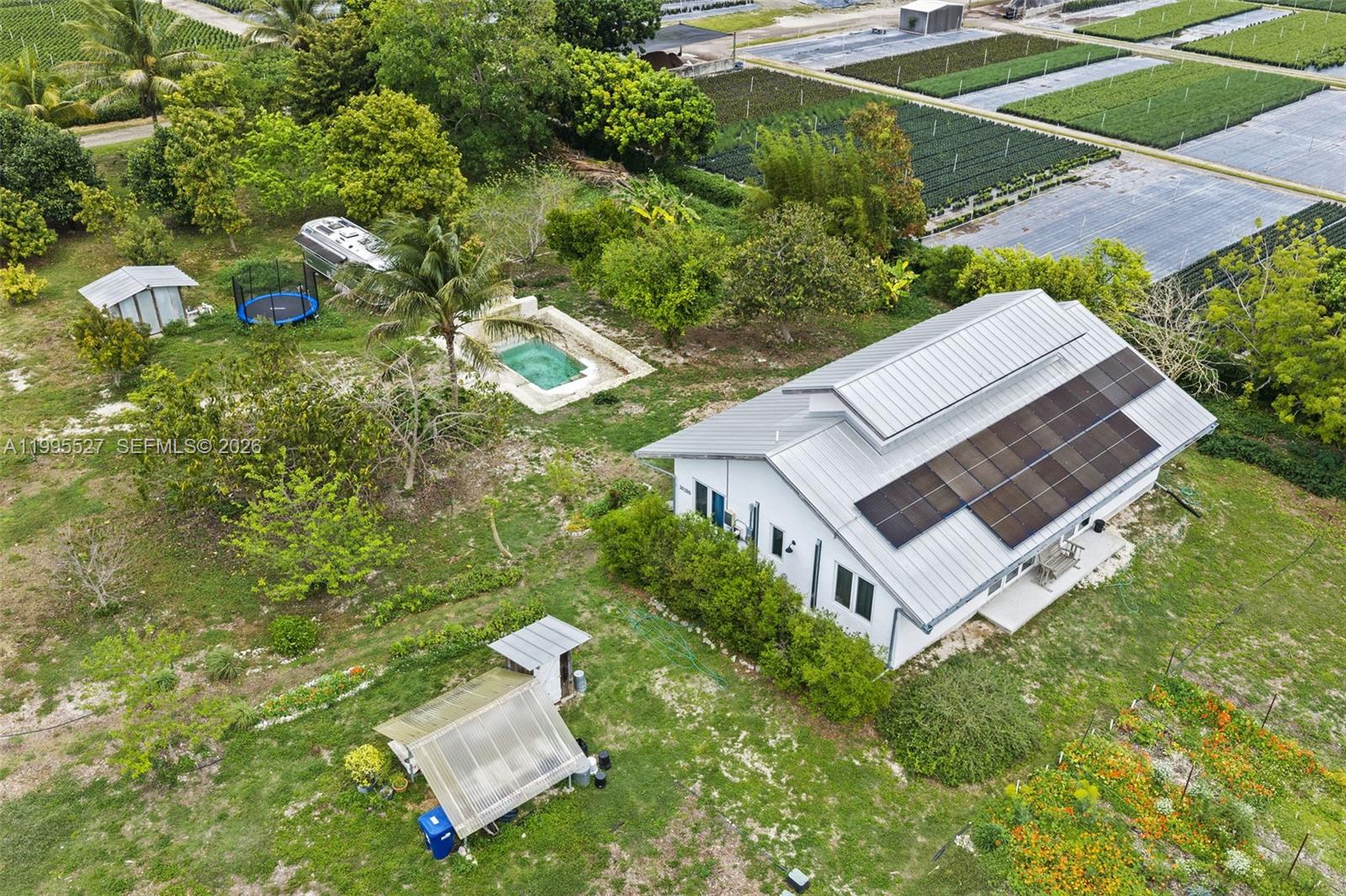 An aerial view shows a house with solar panels, a pool, and surrounding farmland — 20255 SW 154th Ave, Miami FL 33187, MIAMI, FL