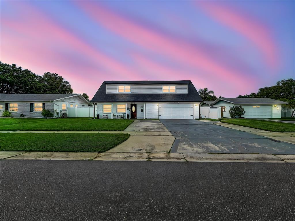 A two-story white house with a dark roof and a two-car garage at dusk — 8407 QUARTZ PLACE, TAMPA, FL
