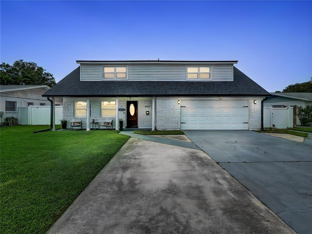 A two-story house with a white brick facade, a dark shingled roof, and a concrete driveway — 8407 QUARTZ PLACE, TAMPA, FL