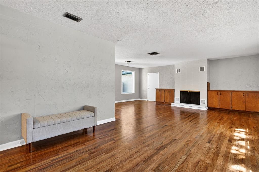 A living room features hardwood floors, a fireplace with built-in cabinets, and a gray bench — 914 NE 11TH AVENUE, GAINESVILLE, FL