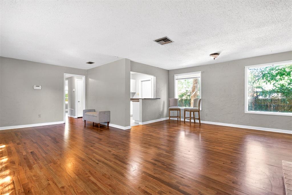 An open living area features hardwood floors, gray walls, and a pass-through to the kitchen — 914 NE 11TH AVENUE, GAINESVILLE, FL