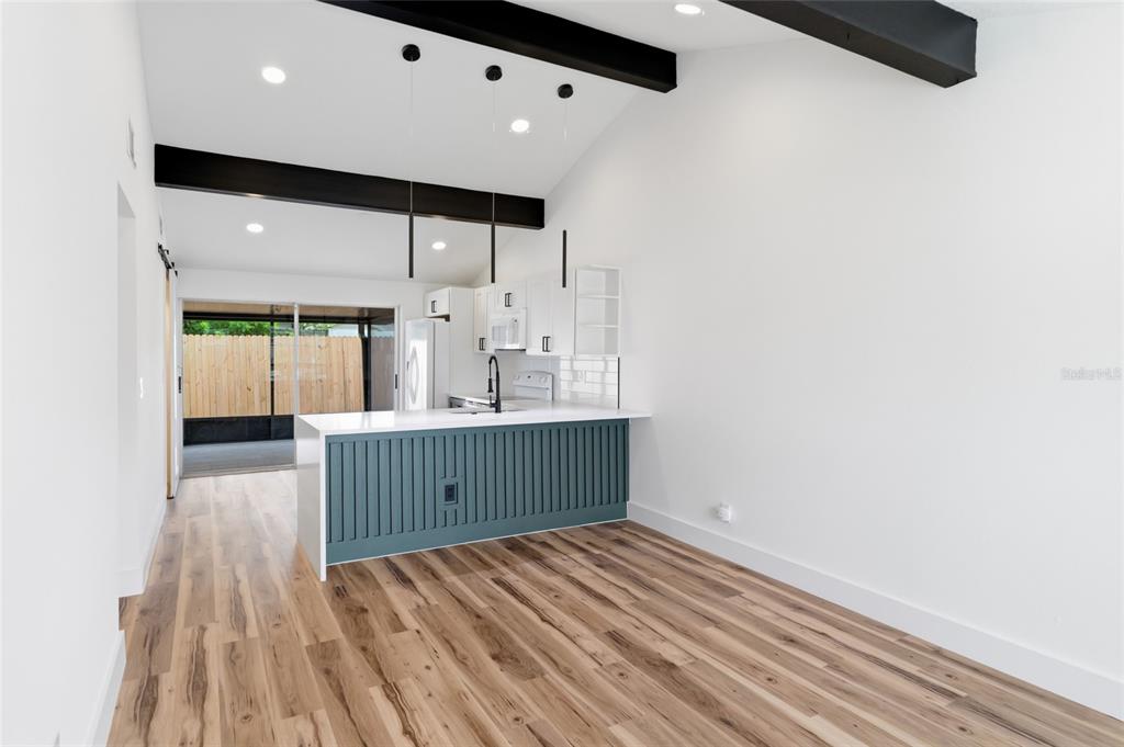 A kitchen with a blue island, white cabinets, and dark wood beams under a vaulted ceiling — 8602 BRIAR GROVE CIR, TAMPA, FL