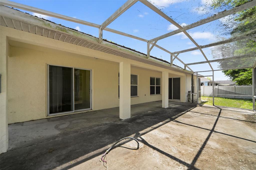 A concrete patio is enclosed by a screened-in lanai attached to the back of a house — 2518 MAYWOOD STREET, EUSTIS, FL