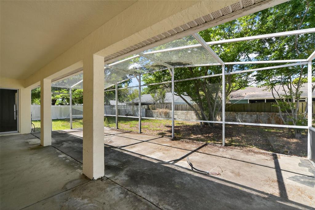A covered concrete patio features a screened-in enclosure overlooking a backyard with trees — 2518 MAYWOOD STREET, EUSTIS, FL