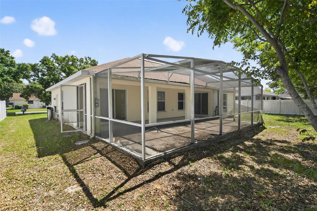 The exterior of a house features a screened-in patio and a concrete slab backyard — 2518 MAYWOOD STREET, EUSTIS, FL
