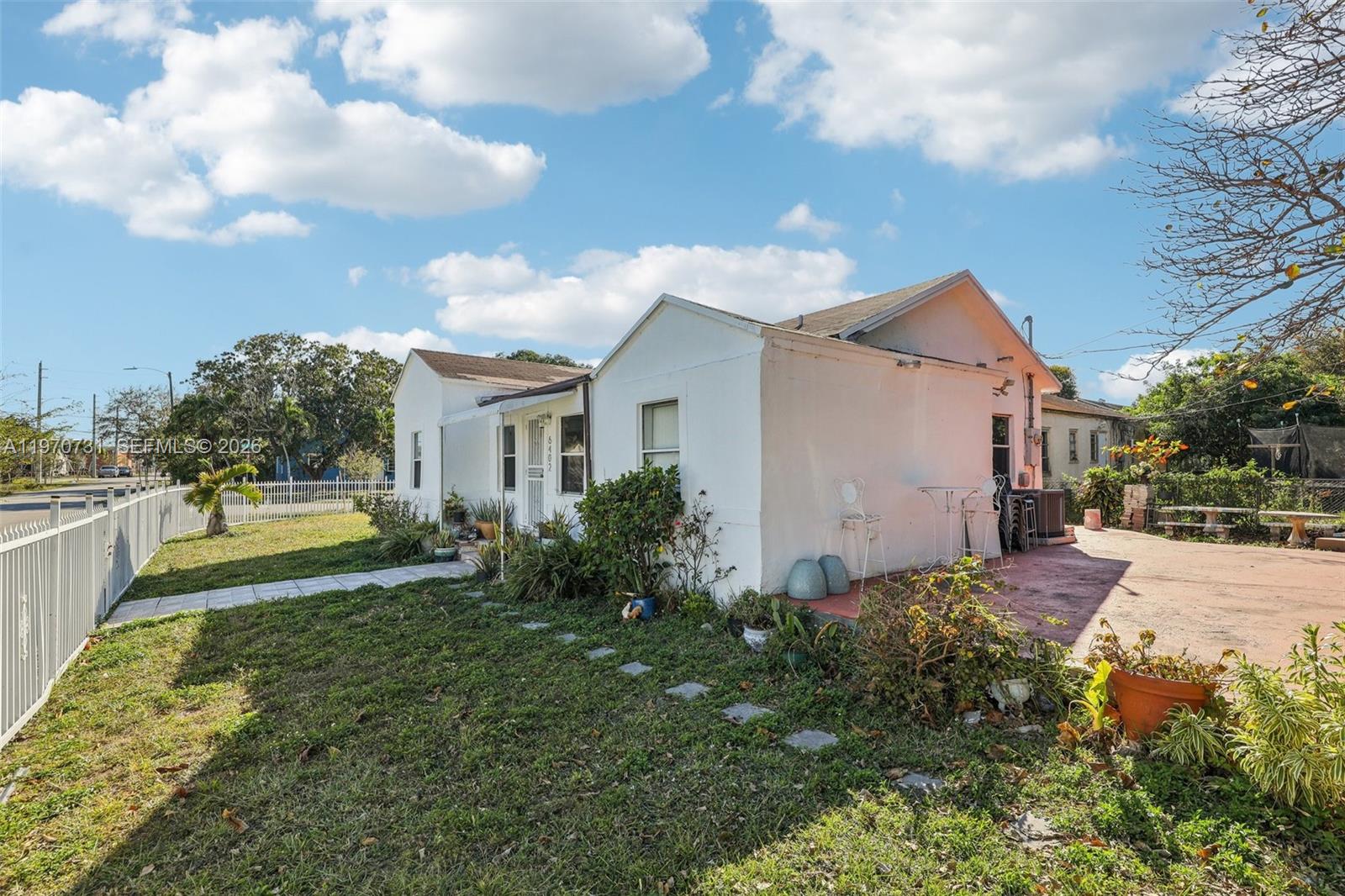 A white, single-story house with a yard, patio, and white fence under a blue sky — 6402 NW 8th Ave, Miami FL 33150, MIAMI, FL