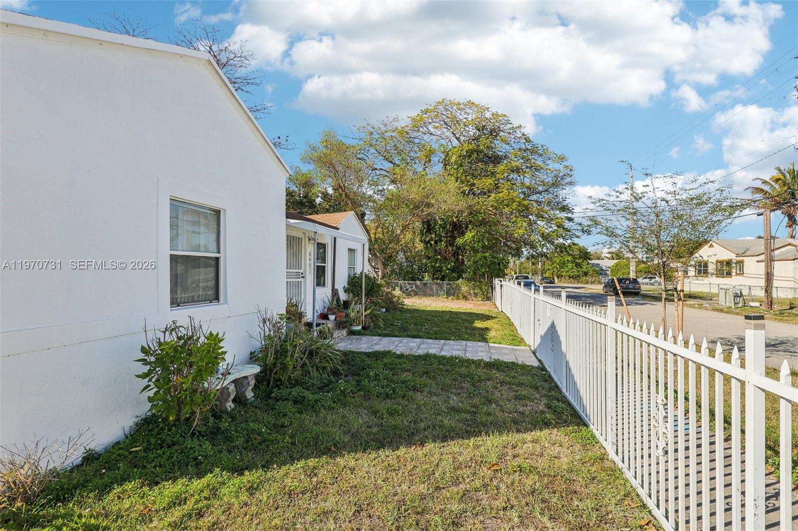 A white house with a side yard and a white metal fence along the street — 6402 NW 8th Ave, Miami FL 33150, MIAMI, FL