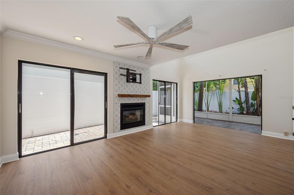 A living room features light wood flooring, a fireplace with patterned tile, and sliding glass doors — 4510 W FIG STREET UNIT C, TAMPA, FL