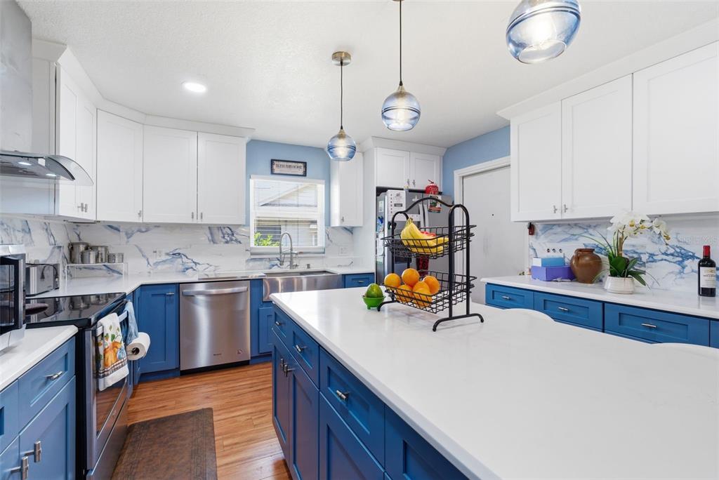 A kitchen features blue lower cabinets, white upper cabinets, a white island, and marble-patterned backsplash — 2605 BRIDLE DRIVE, PLANT CITY, FL