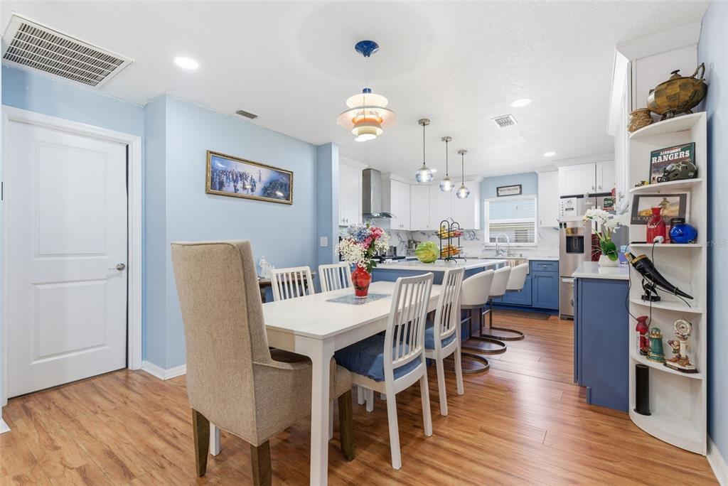 A dining area with a white table and chairs sits adjacent to a blue-accented kitchen — 2605 BRIDLE DRIVE, PLANT CITY, FL