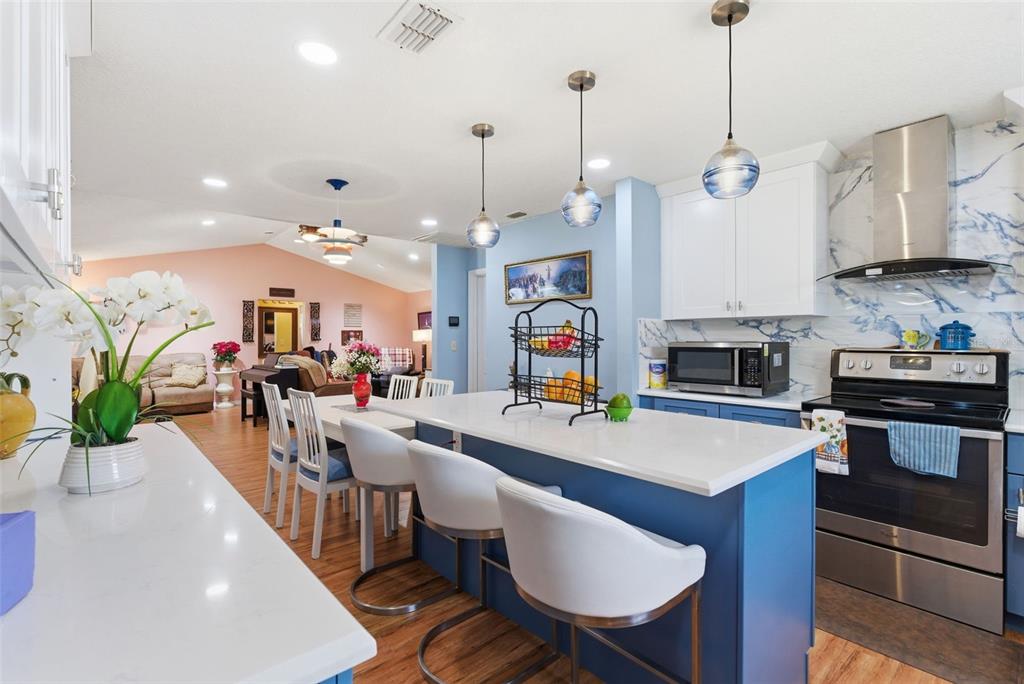 A kitchen with a blue island, white countertops, and pendant lighting opens to a living area — 2605 BRIDLE DRIVE, PLANT CITY, FL