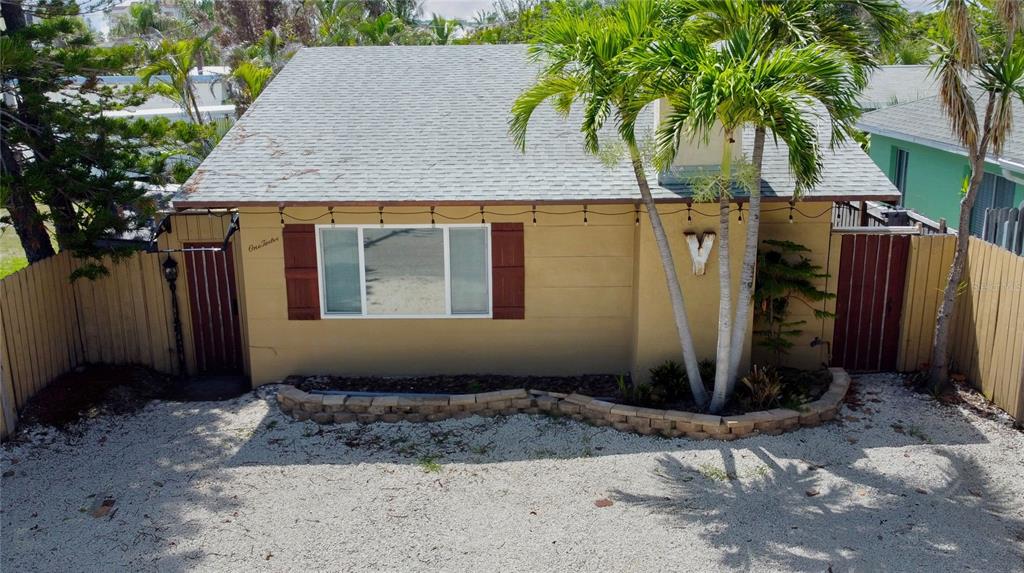 A tan, single-story house with a gray shingled roof, palm trees, and a gravel yard — 112 119TH AVENUE, TREASURE ISLAND, FL