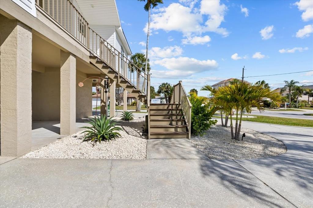 An exterior view of a stilted house with a wooden staircase leading to a deck — 8117 BRIGHTON DRIVE, PORT RICHEY, FL