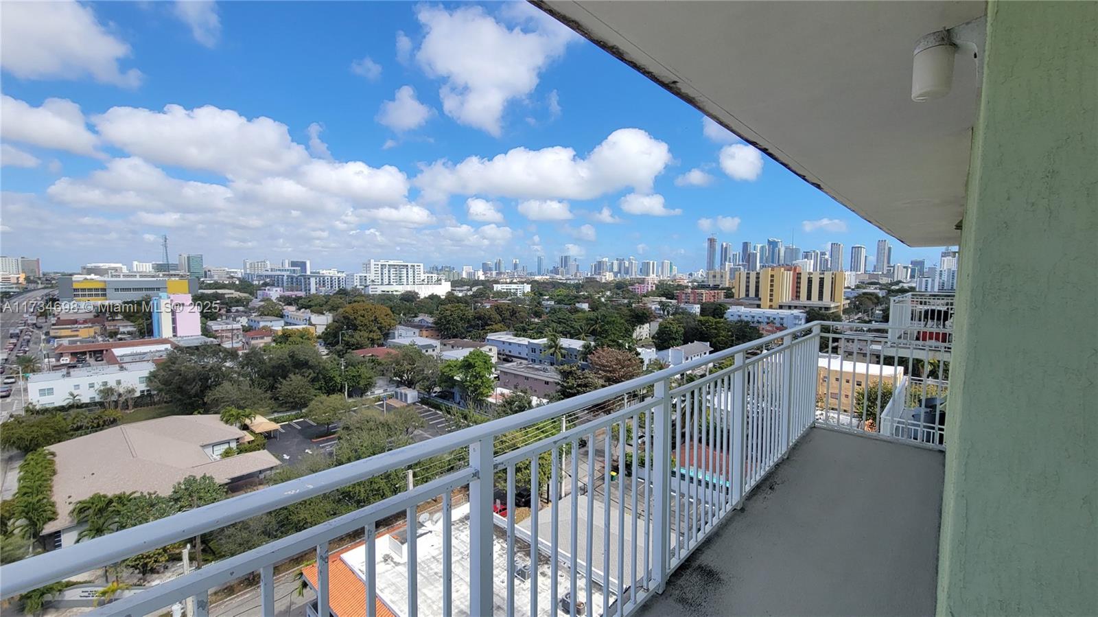 A balcony with a white metal railing overlooks a city skyline under a cloudy sky — 219 NW 12th Ave # 1004, Miami FL 33128, MIAMI, FL
