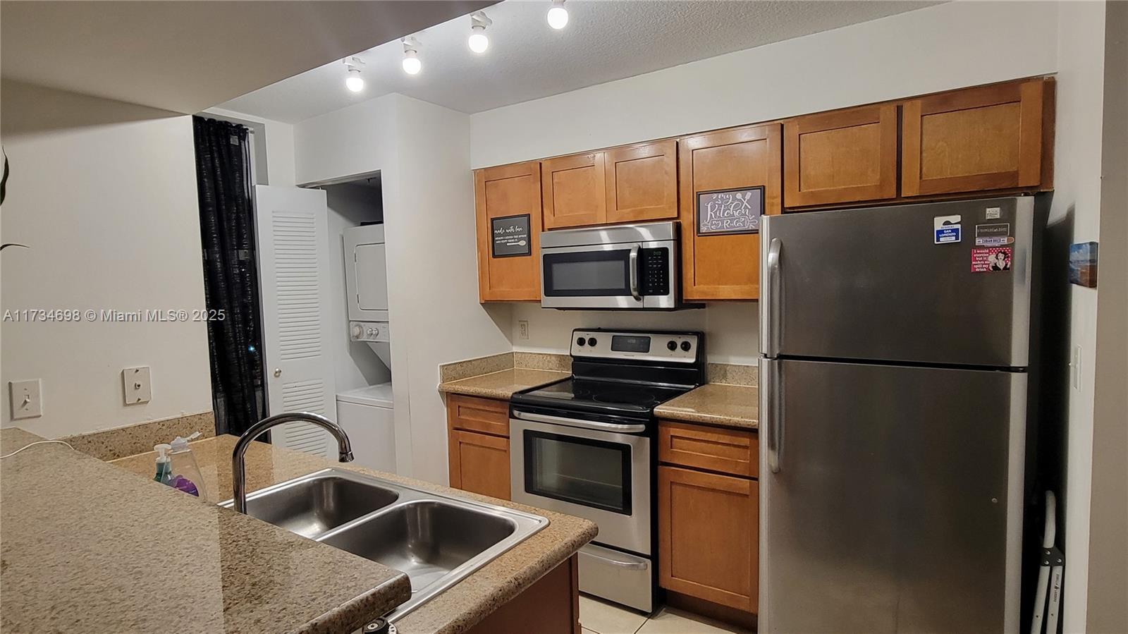 A kitchen features wood cabinets, stainless steel appliances, a double sink, and a laundry closet — 219 NW 12th Ave # 1004, Miami FL 33128, MIAMI, FL