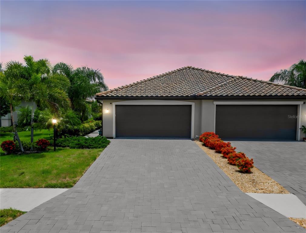 A paved driveway leads to a two-car garage of a house with a tiled roof — 5323 WHITE SAND COVE, BRADENTON, FL